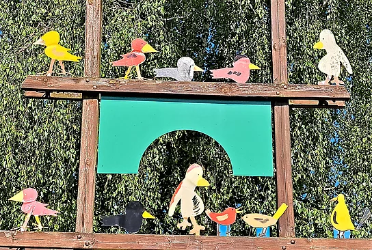 Bunte Holzvögel sitzen auf zwei Holzmasten