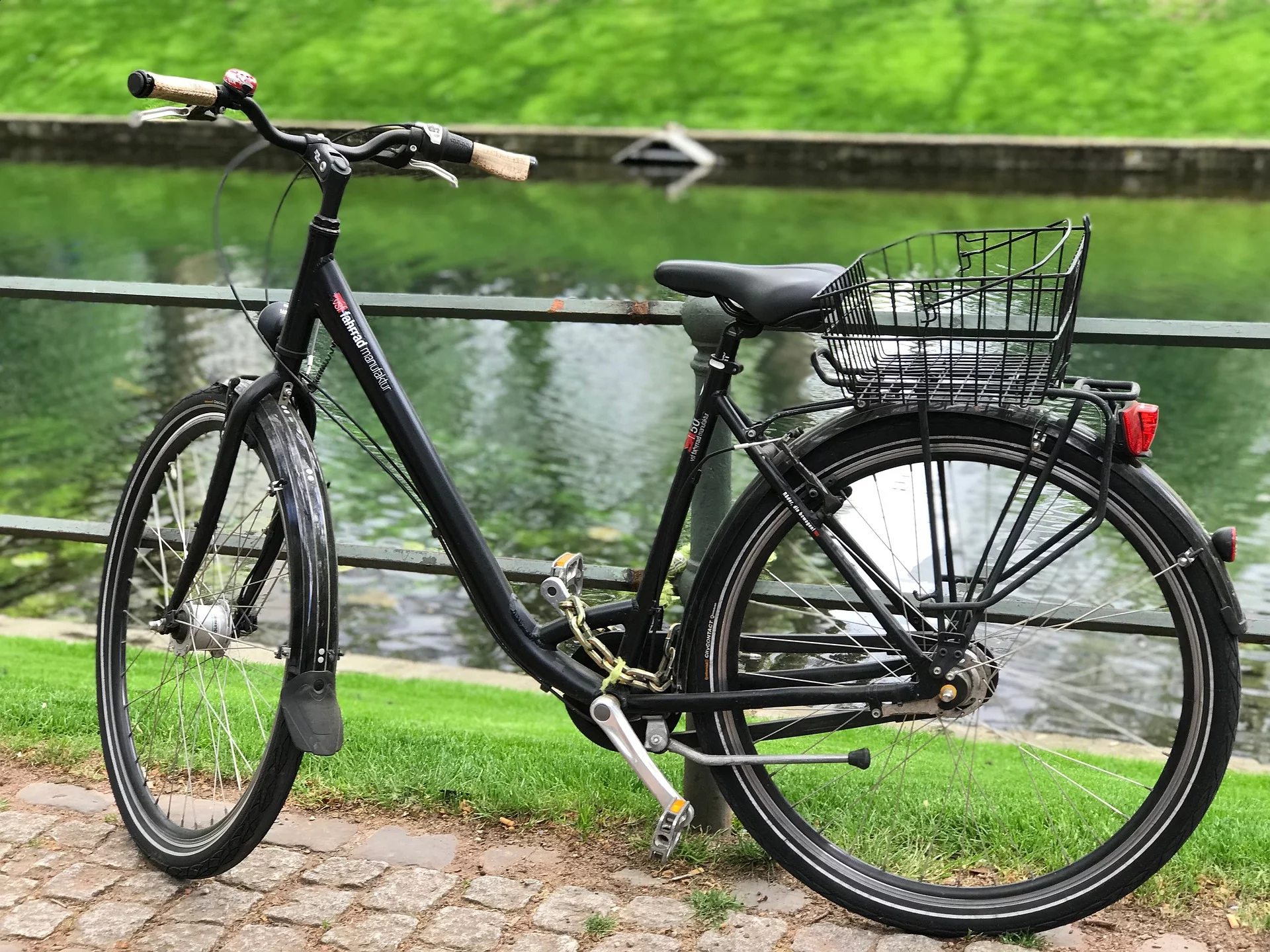 Fahrrad angelehnt an Zaun vor grün gesäumten Fluss