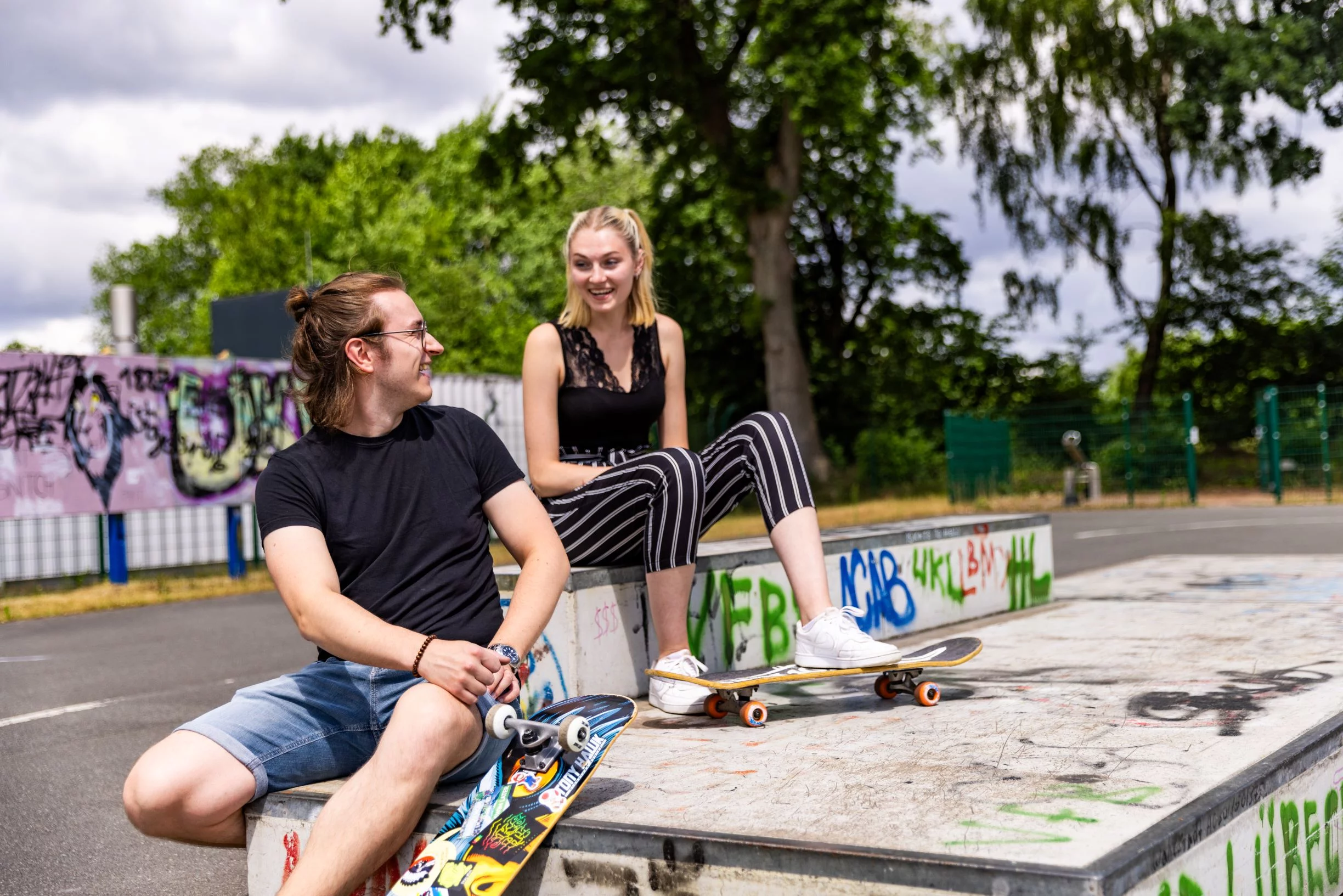 Duo sitzt auf Anhöhe mit Skateboards