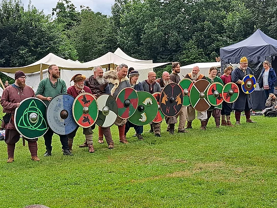 Mittelalterlich gewandete Menschen mit Schildern in einer Reihe 