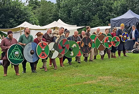 Mittelalterlich gewandete Menschen mit Schildern in einer Reihe