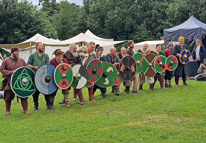 Mittelalterlich gewandete Menschen mit Schildern in einer Reihe 