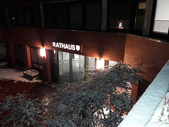 Blick von oben auf den erleuchteten, verschneiten Rathauseingang