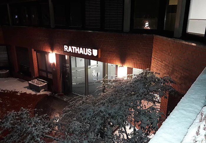 Blick von oben auf den erleuchteten, verschneiten Rathauseingang